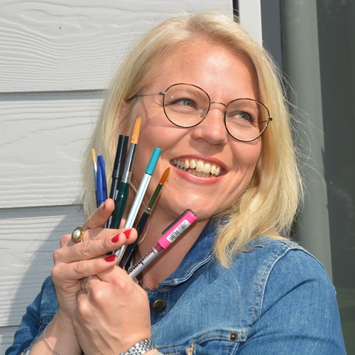 Tina Niemann lacht herzlich und sieht glücklich aus. In den Händen hält sie einen bunten Fächer aus Stiften, Brushpens und Pinseln.