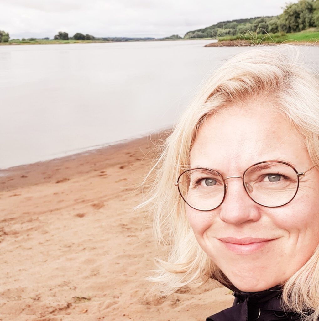 Tina Niemann sitzt am Ufer der Elbe an einem grauen Morgen und genießt dort in aller Ruhe und in Stille ihren Morgenkaffee.