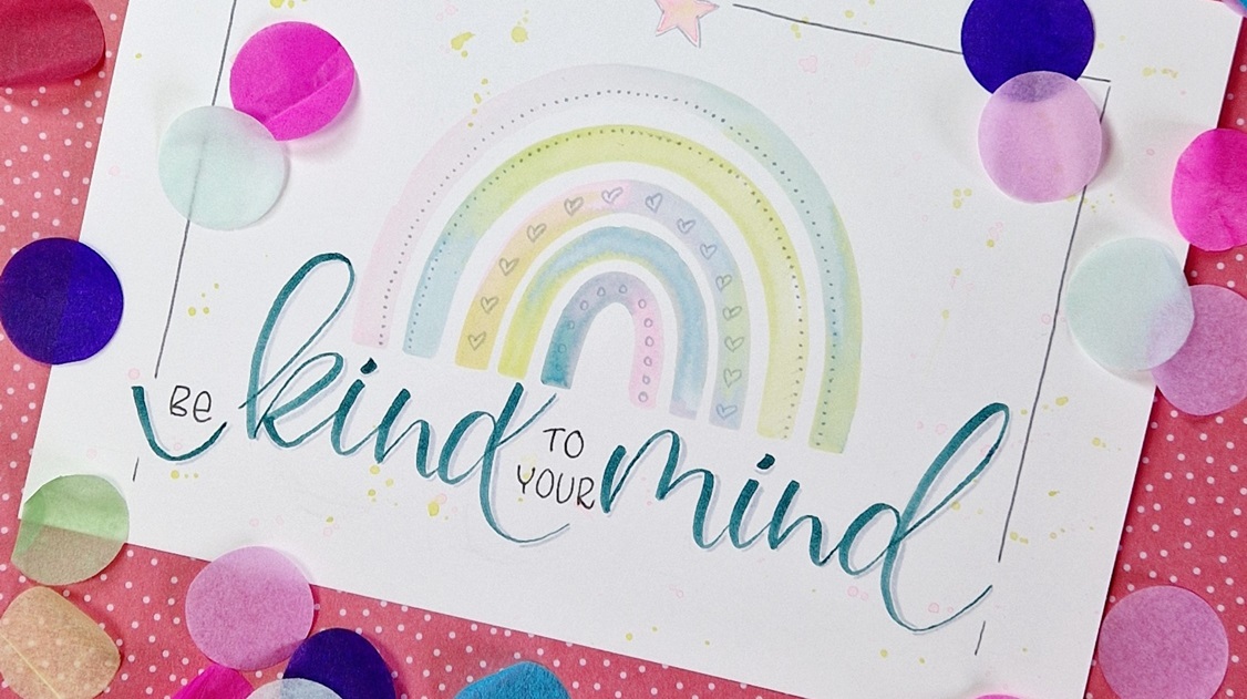 Das Titelbild zeigt einen Aquarell Regenbogen mit dem Handlettering Text "Be kind to your mind" und Konfetti drumherum